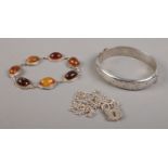 Three pieces of silver jewellery. Includes amber/copal bracelet, bangle and chain with padlock