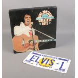 An Elvis Presley greatest hits LP box set along with an enamelled Elvis licence plate.