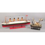 A painted wooden model of HMS Titanic and a fishing trawler. Both mounted on wooden plinths. Titanic