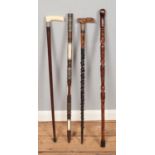 Four craved wooden walking sticks. To include brass and bone inlayed example and a carved bone