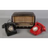 A vintage bakelite radio along with two rotary dial telephones.