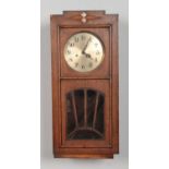 An Art Deco style oak cased wall clock. With Arabic numeral dial, pendulum and key. H: 63.5cm W: