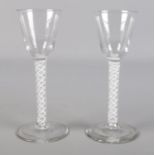 A near pair of 18th century wine glasses with double opaque air twist stems and circular feet.