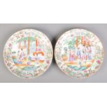A pair of Cantonese famille rose plates, both decorated with figures on a terrace. 25cm diameter.
