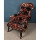 A Victorian spoon back arm chair with carved mask decoration.