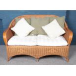 A cane and rattan conservatory suite. Comprising of a two seat sofa, armchair and coffee table. Sofa