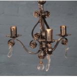 A wrought iron ceiling light with gilt floral decoration and glass droplets.