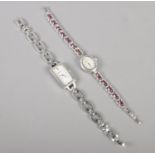 A silver ladies wristwatch set with garnets along with a similar Pulsar example.