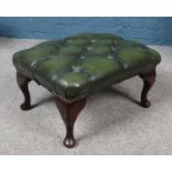 A deep buttoned green leather upholstered footstool.