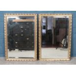 A pair of gilt framed bevel edge wall mirrors. 72.5cm x 50cm.