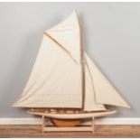 A very large multi-sail model of a yacht, with wooden decking and hull and custom built stand.