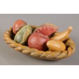 A stoneware basket with collection of assorted pottery fruit.