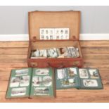 A leather suitcase containing an extremely large collection of vintage world postcards and