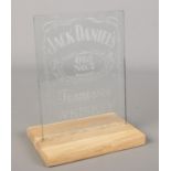 A Jack Daniel's Whiskey etched glass advertising panel on oak stand.