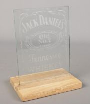 A Jack Daniel's Whiskey etched glass advertising panel on oak stand.