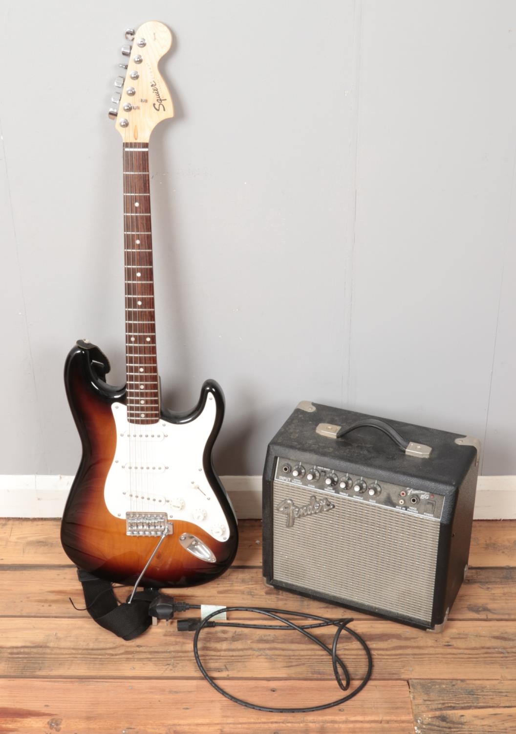 A Squier by Fender electric guitar along with a Fender amplifier.