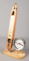A decorative clock/thermometer formed from an antique cotton shuttle and pressure gauge.
