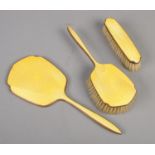 An Art Deco yellow guilloche enamel backed three piece vanity set. Slight chips to the emamel of