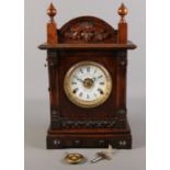 A carved oak Fattorini & Sons mantel clock. Patent automatic alarm. With pendulum and key.