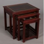 A nest of three mahogany glass top tables.