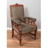 A carved pitch pine arm chair with armorial upholstery.