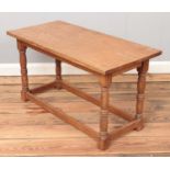 A light oak coffee table with turned supports. (47cm x 84cm x 41cm)