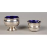 Two silver salt pots, with blue glass liners. Larger example stamped 'Sterling' to base, the other