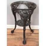 A painted cast iron tavern table base with mask decoration.