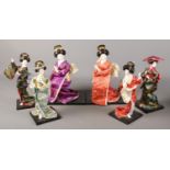 A box of six decorative Geisha dolls on stands.