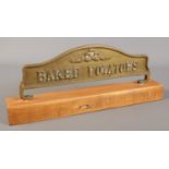 A brass Baked Potatoes sign mounted to wooden base.