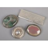 A WMF white metal stamp case along with three brooches. Includes a silver target brooch.