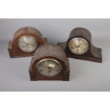 A trio of mantle clocks with roman numeral faces.