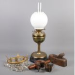 A brass oil lamp along with a small bag chandelier and vintage hand tools.