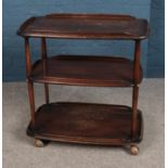 A Ercol three tier dark elm drinks trolley, complete with wheels.