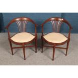 A pair of upholstered tub chairs with pierced backs.