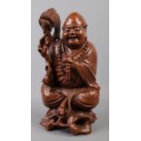 A large Chinese carved hardwood figure depicting a seated man clutching beaded necklace. 33cm