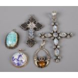 Five silver pendants; to include crucifix, scarab beetle and ceramic examples. Slight damage to