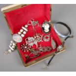 A case of costume jewellery. Includes silver pendant, marcasite set watch, brooches etc.