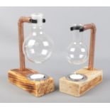 Two copper pipe and florence flask tea light holders mounted on wooden bases.