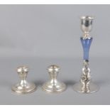 A pair of weighted sterling silver candlesticks with larger white metal example featuring leaf