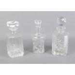 Three cut glass decanters with matching stoppers. Tallest decanter approx. 25cm high including