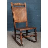 An oak and ply panel and spindle back rocking chair.