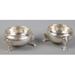A pair of silver salts raised on three stepped feet. Assayed London 1857 and 1852. 198g.