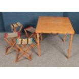 A wooden folding picnic set with table with four fabric stools. One stool is damaged.
