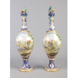 A pair of Majolica ewers decorated with classical scenes and having intertwined serpent handles.