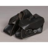 A pair of black leather motorbike saddle bags with buckle closures.