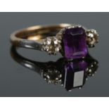 An 18ct gold and platinum ring set with a single square cut amethyst flanked by two diamonds. Size
