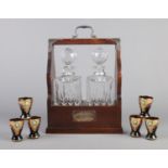A lockable mahogany two bottle tantalus, together with six coloured glasses with gilt edge and