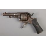 A late 19th/early 20th century pin fire revolver with engraved six shot cylinder and chequered grip.