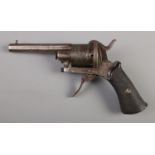 A late 19th/early 20th century pin fire revolver with engraved six shot cylinder and chequered grip.